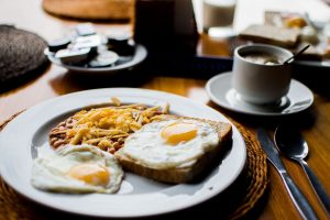 A plate of over easy eggs with toast with a cup of coffee.