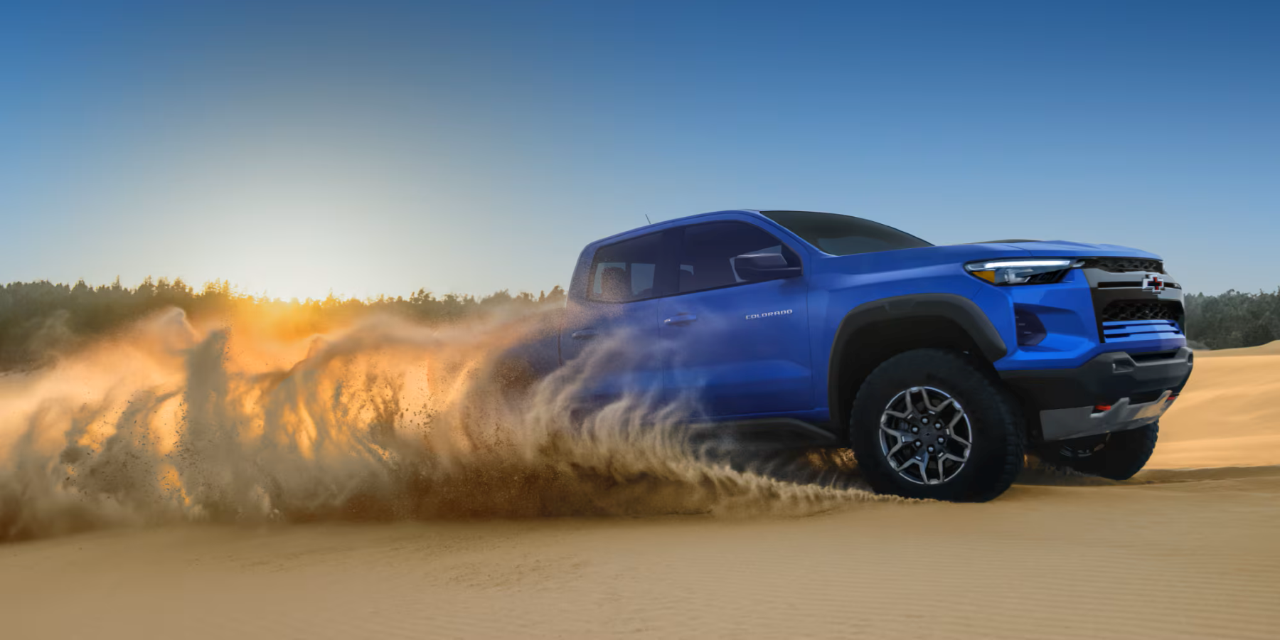 Metallic Blue 2026 Chevrolet Colorado pickup truck driving in desert sand